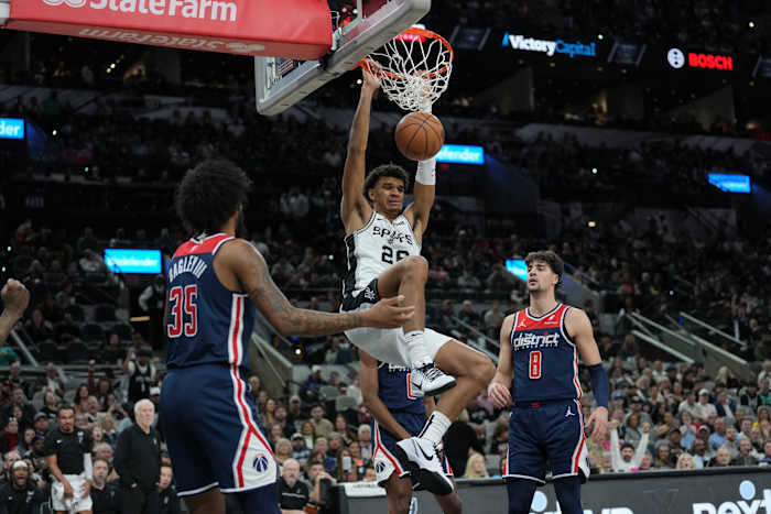 Jan 29, 2024; San Antonio, Texas, USA; San Antonio Spurs forward Dominick Barlow (26) dunks between Washington Wizards forwards Marvin Bagley III (35) and Deni Avdija (8) in the first half at Frost Bank Center.